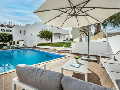 an outdoor patio with a pool and an umbrella at Holiday Home Lima - VIP Properties by Interhome in Albufeira