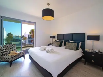 a bedroom with a large white bed and a chair at Villa Pires - VIP Properties by Interhome in Albufeira