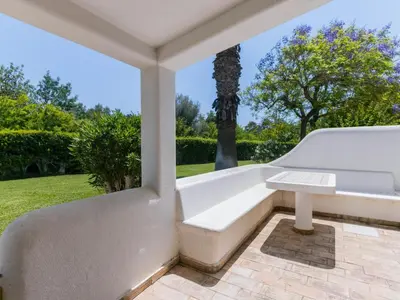 a white bench on a patio with a statue at AL - Aldeia do Golfe Retreat in Vilamoura