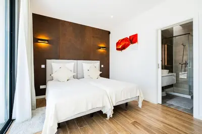 a bedroom with a large white bed and a bathroom at Villa Kambole in Albufeira