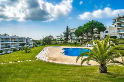 a swimming pool in a park with a palm tree at Monte Balaia AT19 Duplex - Pool View Olhos de Agua in Olhos de Água