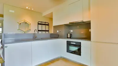 a kitchen with white cabinets and a sink at Apartamento T2 novo e espaçoso em Vilamoura in Vilamoura