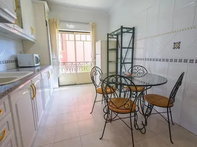 a kitchen with a table and chairs in a kitchen at Oura Sunrise 16 Apartment by Stay ici Algarve Holiday Rental in Albufeira