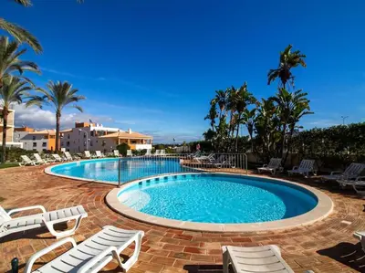 a large swimming pool with chairs and palm trees at Globe 33 Apartment by Stay ici Algarve Holiday Rental in Albufeira