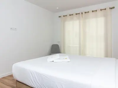 a bedroom with a large white bed and a chair at Panoramic E Apartment by Stay ici Algarve Holiday Rental in Albufeira