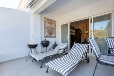 a porch with three striped chairs and a table at Cozy 2 BDR W/Balcony in Vale do Lobo by LovelyStay in Vale do Lobo