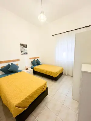 two beds in a white room with yellow sheets at Casa Brito in Albufeira