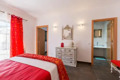 a bedroom with a red bed and a bathroom at VILA RUINAS GAMITO in Guia