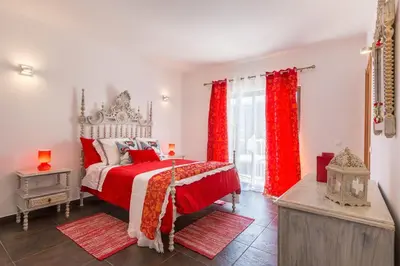 a bedroom with a red and white bed and a window at VILA RUINAS GAMITO in Guia
