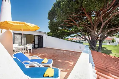 a patio with chairs and an umbrella and a tree at Mng Elliott25 in Vale do Lobo