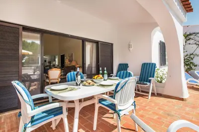 a patio with a table and chairs and a swimming pool at Mng Elliott13 in Vale do Lobo
