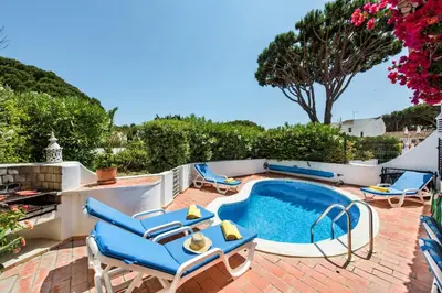 a patio with a swimming pool and blue chairs at Mng Elliott76 in Vale do Lobo