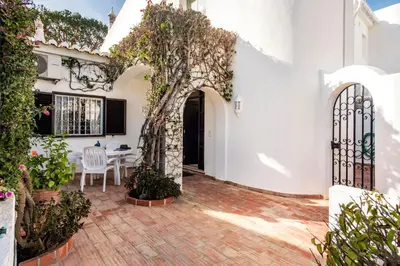 a white house with an archway and a table and chairs at Mng Elliott72 in Vale do Lobo