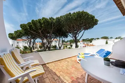 a balcony with a table and chairs and trees at Mng Elliott71 in Vale do Lobo