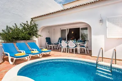 a patio with a swimming pool and chairs and a table at Mng Elliott53 in Vale do Lobo