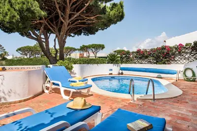 a patio with blue chairs and a swimming pool at Mng Elliott37 in Vale do Lobo