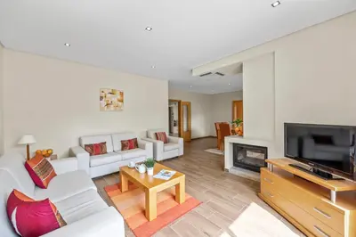 a living room with a white couch and a tv at Tranquil Hideaway Olhos de Agua in Faro