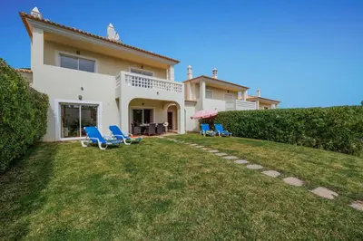 a villa with a yard with blue chairs at Tranquil Hideaway Olhos de Agua in Faro