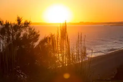 a sunset on the beach with the sun setting over the water at Tranquil Hideaway Olhos de Agua in Faro