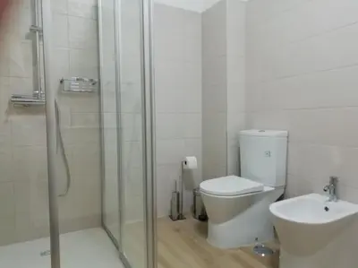 a bathroom with a shower and a toilet and a sink at Apartamento laranja Quarteira in Quarteira