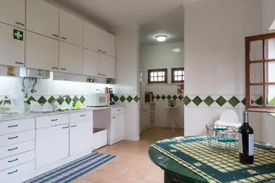 a kitchen with white cabinets and a table with a bottle of wine at Akisol Faro Relax in Faro