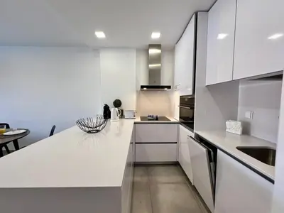 a white kitchen with white cabinets and a table at Albufeira Twins 3 With Pool by Homing in Albufeira