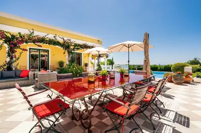 a table with chairs and an umbrella on a patio at TheBougainVilla our Oceanview Villa in the Hills in Boliqueime