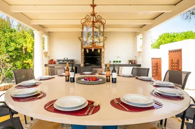 a dining room table with plates and wine bottles on it at TheBougainVilla our Oceanview Villa in the Hills in Boliqueime