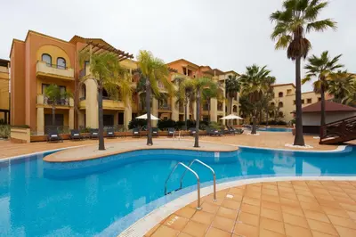 a pool at a resort with palm trees and buildings at The Residences Vilamoura in Vilamoura