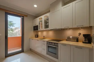 a kitchen with white cabinets and a sink and a window at The Residences Vilamoura in Vilamoura