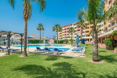 a pool with chairs and palm trees in a resort at BelaVista Tenis SweetHouse in Albufeira