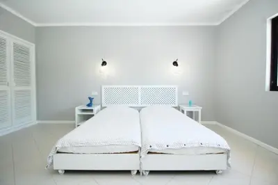 a white bedroom with a white bed and two tables at BelaVista Tenis SweetHouse in Albufeira