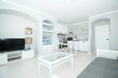 a white living room with a tv and a table at BelaVista Tenis SweetHouse in Albufeira