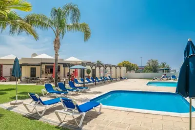 a pool with blue chairs and palm trees at BelaVista Tenis SweetHouse in Albufeira