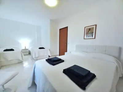 a white bedroom with two beds with towels on them at Beachfront flat with pool in Quarteira