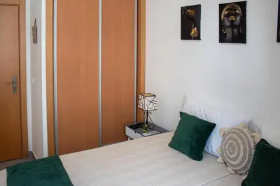 a bedroom with a bed with two green pillows at Casa Amarela - Conforto e localização central! in Faro