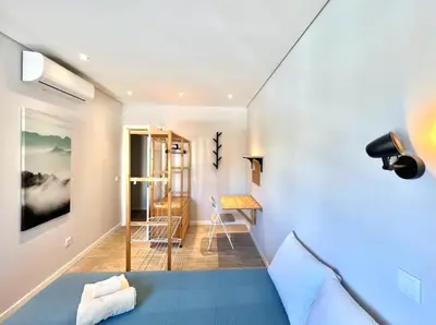 a room with a blue bed and a hallway at Campus 121 - Rooms in Faro