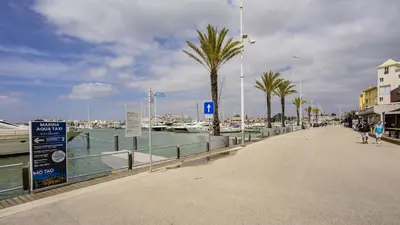 a walkway next to a marina with palm trees at T3 Triplex Vista Mar Marina de Vilamoura-Greice Homes in Vilamoura