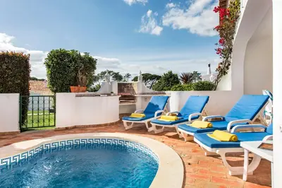 a swimming pool with blue chairs next to a house at Mng Elliott55 in Vale do Lobo