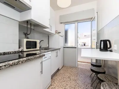 a white kitchen with white cabinets and a microwave at Akisol Faro Sunny in Faro