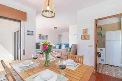 a dining room with a table with a vase of flowers at Quarteira Mar à Vista T1 in Quarteira