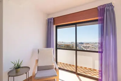 a room with a chair and a large window at Quarteira Mar à Vista T1 in Quarteira