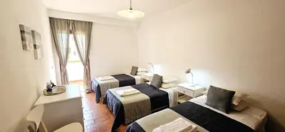 a hotel room with three beds and a window at Beach House Vidinha in Albufeira