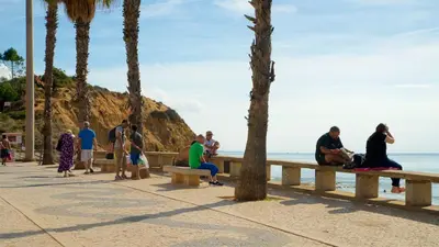 people sitting on a bench at the beach at Beach House Vidinha in Albufeira