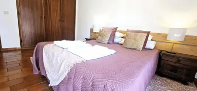 a bedroom with a purple bed with two towels on it at Beach House Vidinha in Albufeira