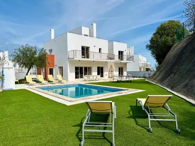 a villa with a swimming pool and two chairs at Vila Nalia in Albufeira