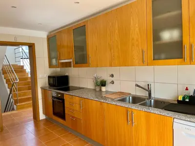 a kitchen with wooden cabinets and a stainless steel sink at Vila Nalia in Albufeira