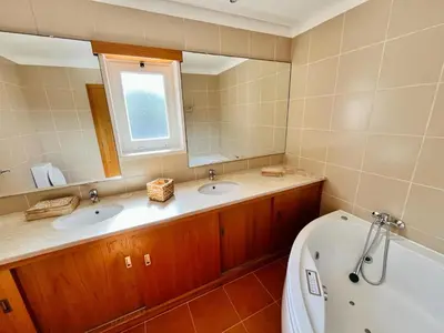 a bathroom with two sinks and a tub and a window at Vila Nalia in Albufeira