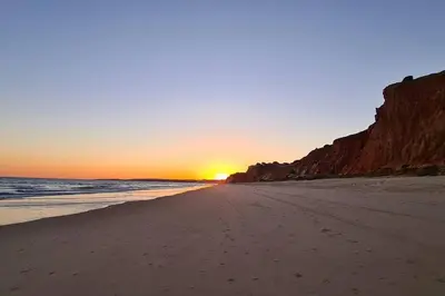 a beach with the sun setting on the horizon at Casa da Aldeia in Olhos de Água