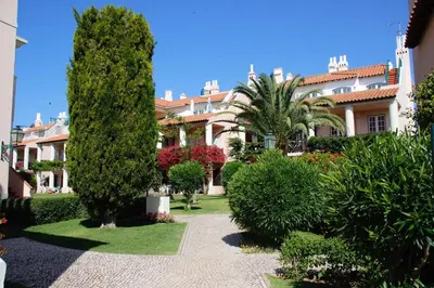 a garden with trees and bushes in front of a building at Old Village, 2 bedrooms, 5 ppl, Beach, Golf, Padel in Vilamoura